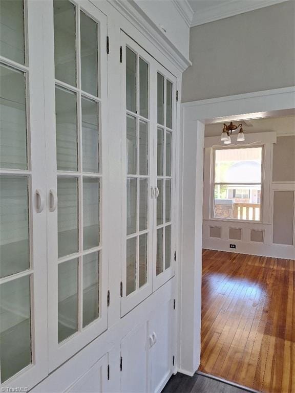 doorway featuring a notable chandelier, ornamental molding, and dark hardwood / wood-style flooring