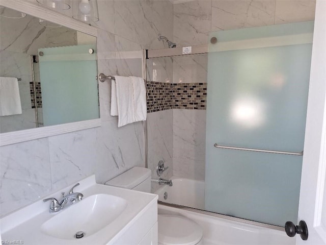 full bathroom with vanity, toilet, tile walls, and bath / shower combo with glass door