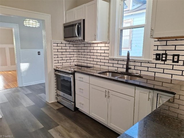 kitchen featuring white cabinetry, stainless steel appliances, and dark stone counters