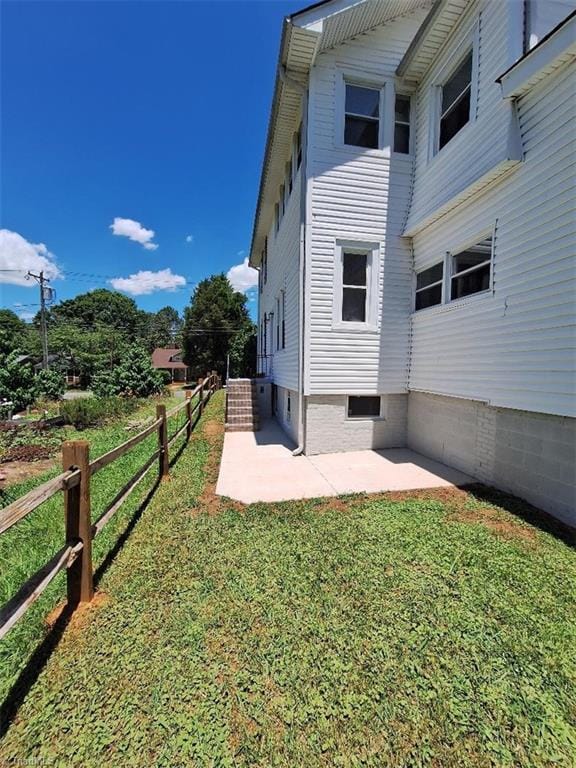 view of side of property with a patio and a lawn