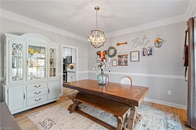 dining room with a chandelier, crown molding, and light hardwood / wood-style flooring