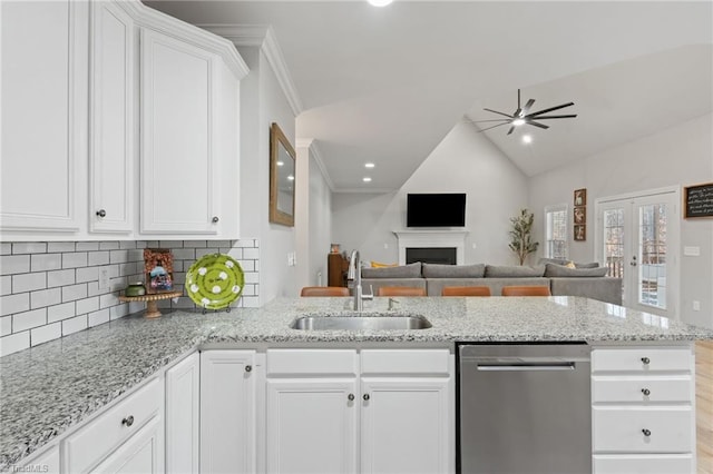 kitchen with dishwasher, sink, white cabinets, and lofted ceiling