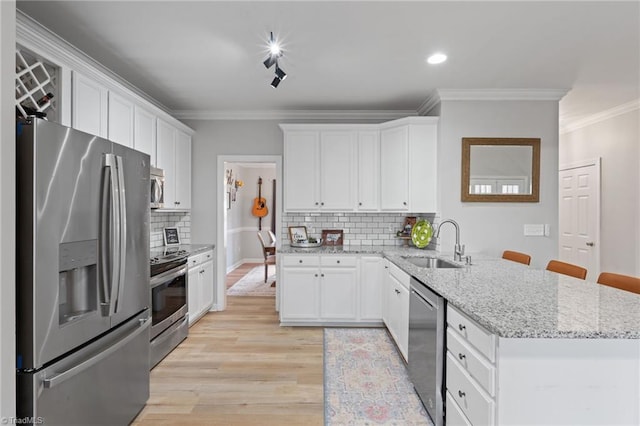 kitchen with tasteful backsplash, sink, white cabinets, and appliances with stainless steel finishes