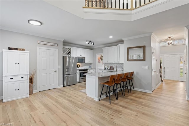 kitchen featuring backsplash, white cabinets, sink, kitchen peninsula, and stainless steel appliances