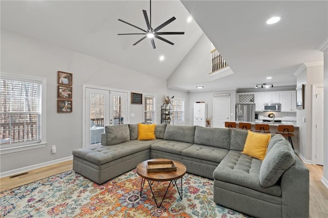 living room with ceiling fan, crown molding, high vaulted ceiling, and light hardwood / wood-style floors