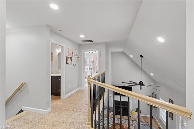 corridor with light colored carpet and vaulted ceiling