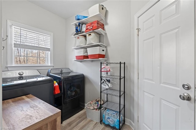 laundry room with separate washer and dryer and light hardwood / wood-style floors