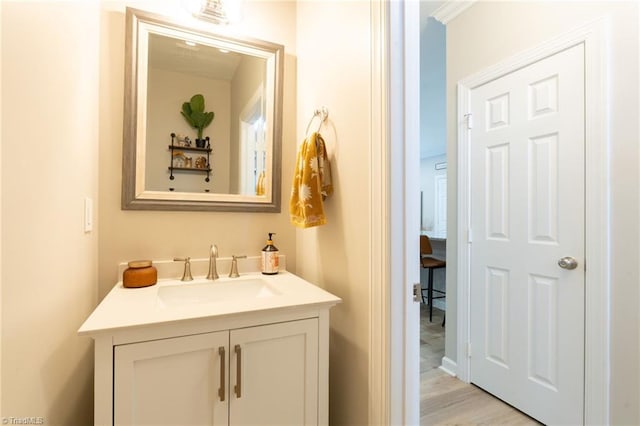 bathroom with hardwood / wood-style floors, vanity, and crown molding