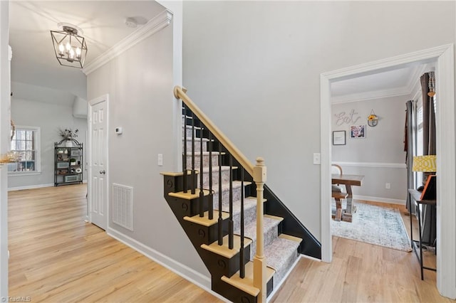 staircase featuring a notable chandelier, wood-type flooring, and crown molding