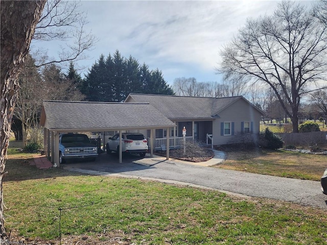 ranch-style home with an attached carport, driveway, a front yard, and roof with shingles