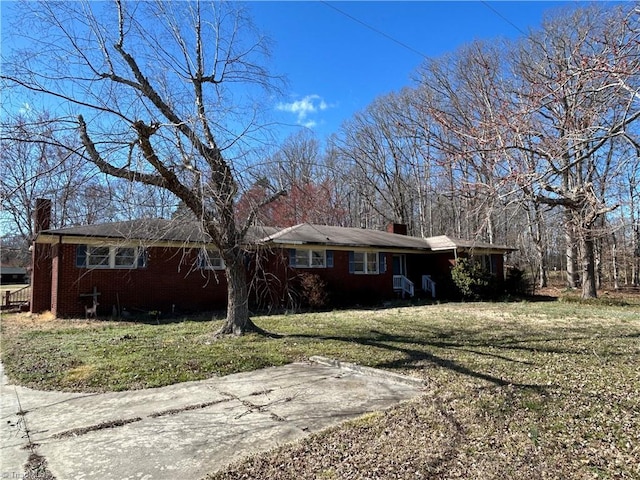 view of front of house featuring brick siding, a chimney, and a front yard