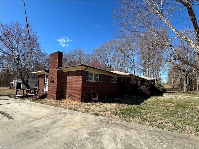 view of side of property featuring crawl space, a chimney, and brick siding