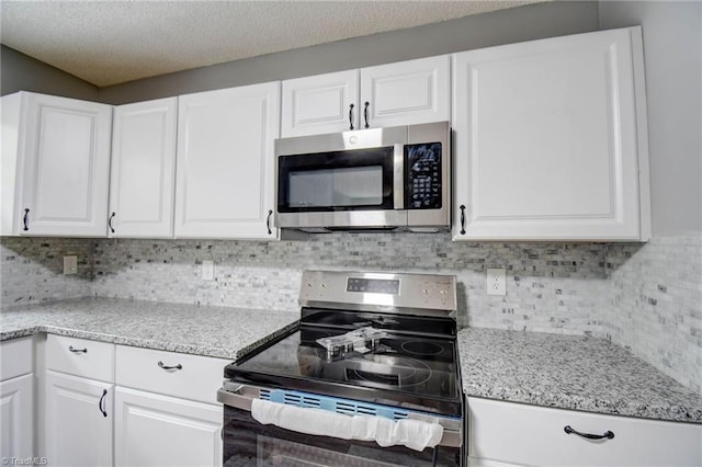 kitchen featuring tasteful backsplash, white cabinetry, and stainless steel appliances