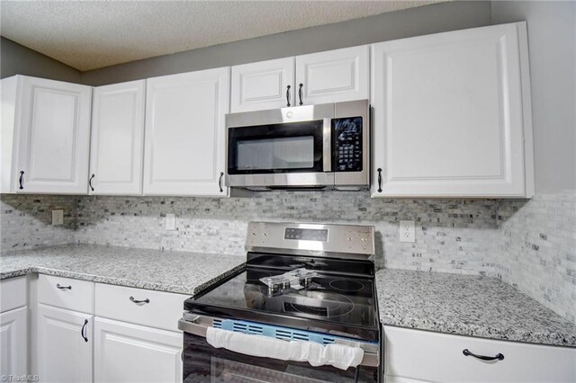 1638 Colonial Dr, Salisbury, NC 28144 - kitchen featuring stainless steel appliances, white cabinets, backsplash, light stone counters, and a textured ceiling