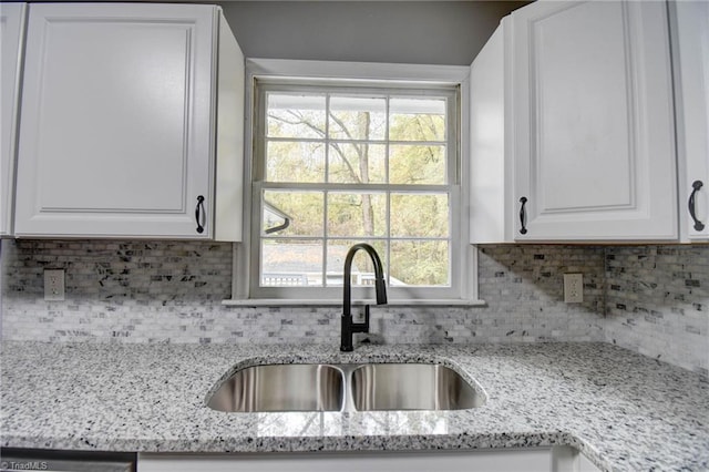 kitchen with white cabinets, sink, light stone counters, and tasteful backsplash