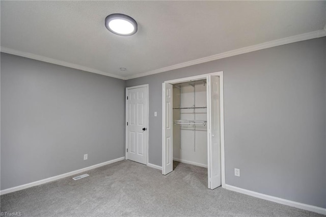 unfurnished bedroom with ornamental molding, light colored carpet, and a closet