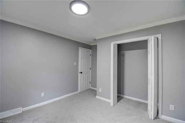 unfurnished bedroom with light colored carpet, a closet, and crown molding