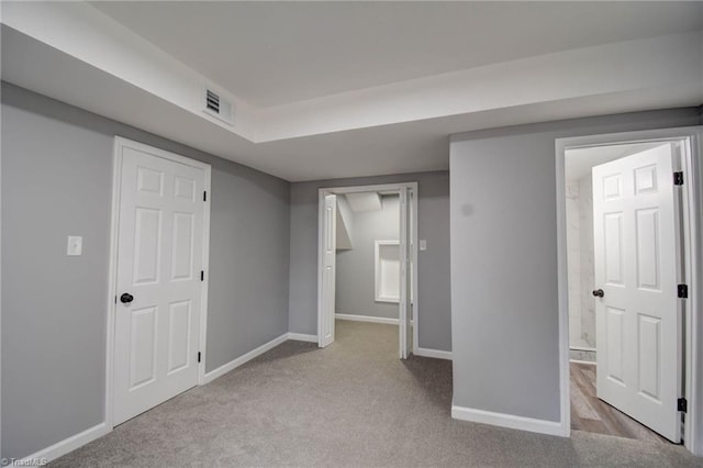 unfurnished bedroom featuring connected bathroom, a closet, and light carpet