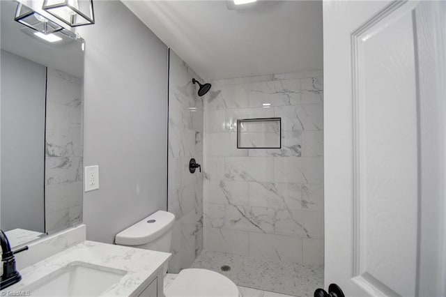 bathroom with toilet, vanity, and tiled shower