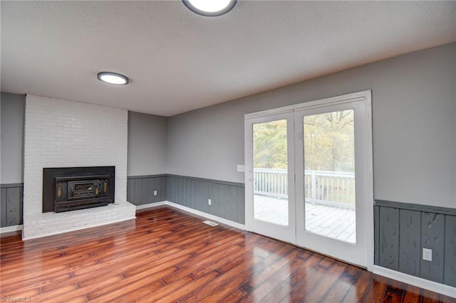 1638 Colonial Dr, Salisbury, NC 28144 - unfurnished living room featuring wood finished floors, a wainscoted wall, a textured ceiling, and a brick fireplace