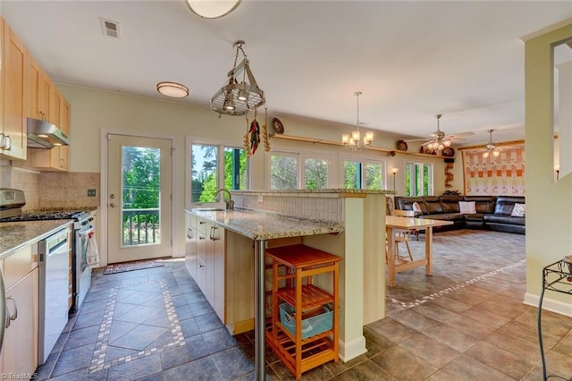 kitchen with under cabinet range hood, visible vents, range with gas stovetop, and a wealth of natural light