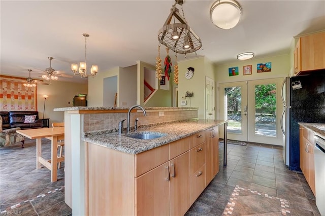kitchen with decorative backsplash, a sink, light stone counters, light brown cabinets, and stainless steel appliances