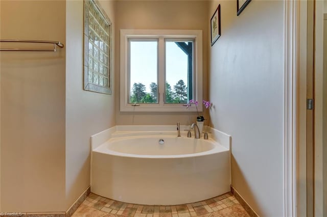bathroom featuring baseboards and a bath