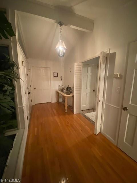 corridor with wood-type flooring and vaulted ceiling