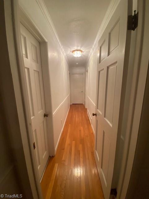 hallway with crown molding and light hardwood / wood-style flooring