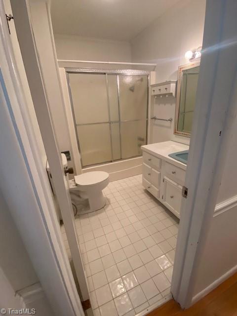 full bathroom featuring enclosed tub / shower combo, vanity, tile patterned flooring, and toilet