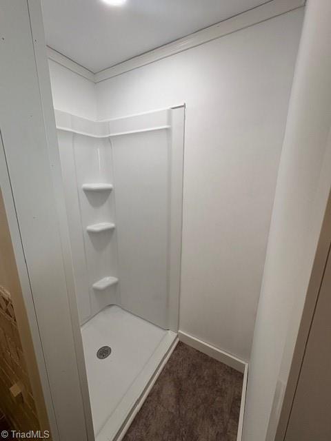 full bathroom featuring baseboards and a shower stall