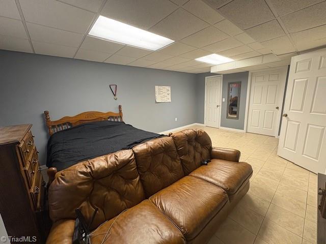 bedroom with light tile patterned flooring, baseboards, and a drop ceiling