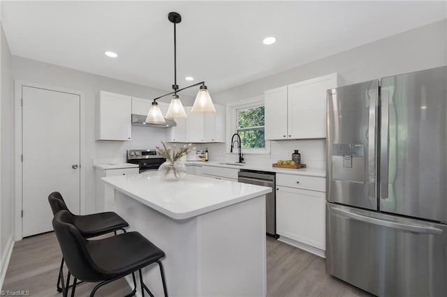 kitchen featuring light wood-type flooring, a kitchen island, hanging light fixtures, stainless steel appliances, and white cabinets