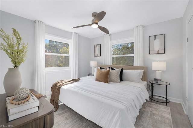 bedroom with multiple windows, wood-type flooring, and ceiling fan