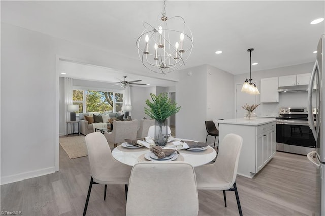 dining space featuring ceiling fan with notable chandelier and light hardwood / wood-style floors