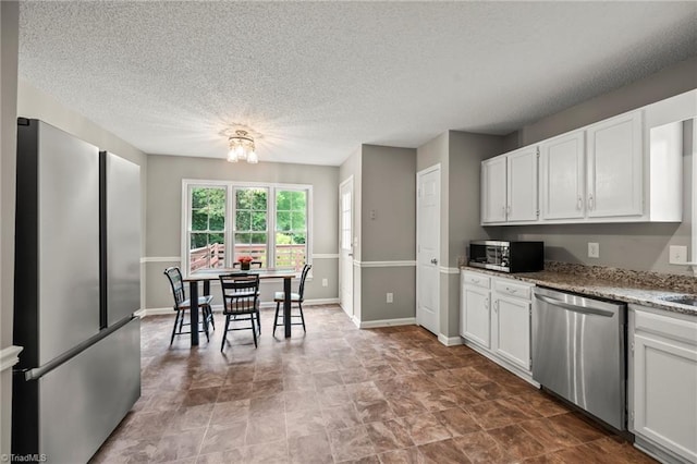 7145 Franklin Rd, Lewisville, NC 27023 - kitchen featuring stainless steel appliances, white cabinets, a textured ceiling, a chandelier, and light stone counters