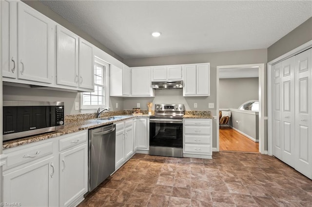 7145 Franklin Rd, Lewisville, NC 27023 - kitchen featuring appliances with stainless steel finishes, under cabinet range hood, white cabinetry, light stone countertops, and recessed lighting