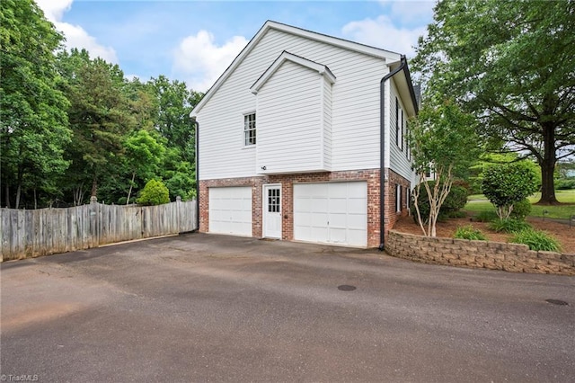 7145 Franklin Rd, Lewisville, NC 27023 - view of side of home featuring asphalt driveway, brick siding, and an attached garage