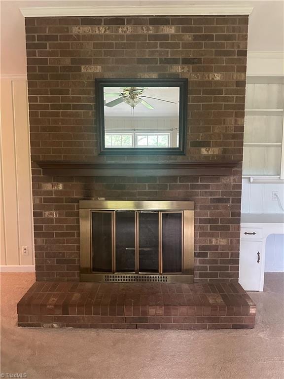 interior details featuring a fireplace, ceiling fan, and carpet