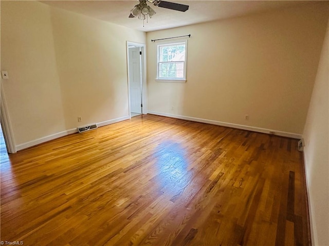 unfurnished room featuring baseboards, a ceiling fan, visible vents, and wood finished floors