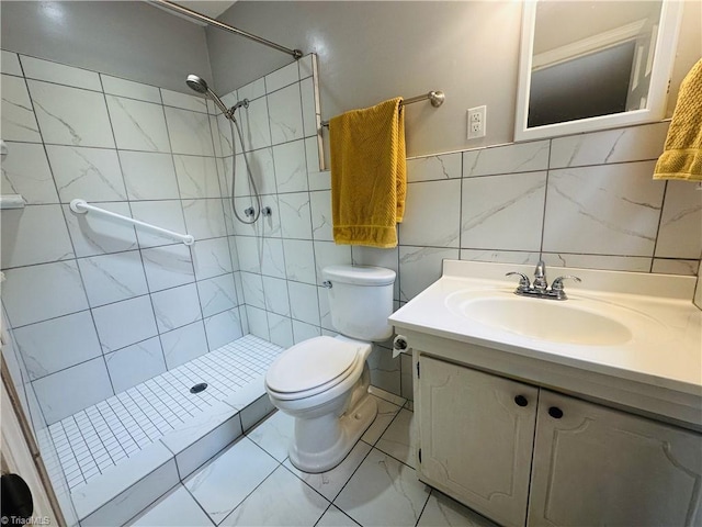 bathroom with a tile shower, vanity, and toilet