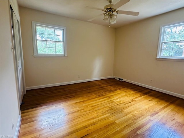 unfurnished room featuring baseboards, visible vents, and wood finished floors