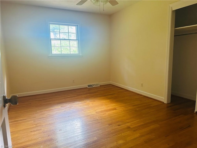 unfurnished bedroom featuring a closet, visible vents, wood finished floors, and baseboards
