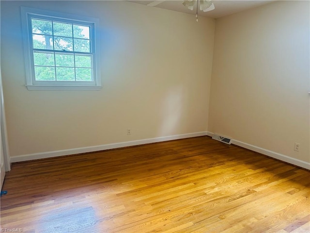 spare room with light wood finished floors, baseboards, a ceiling fan, and visible vents