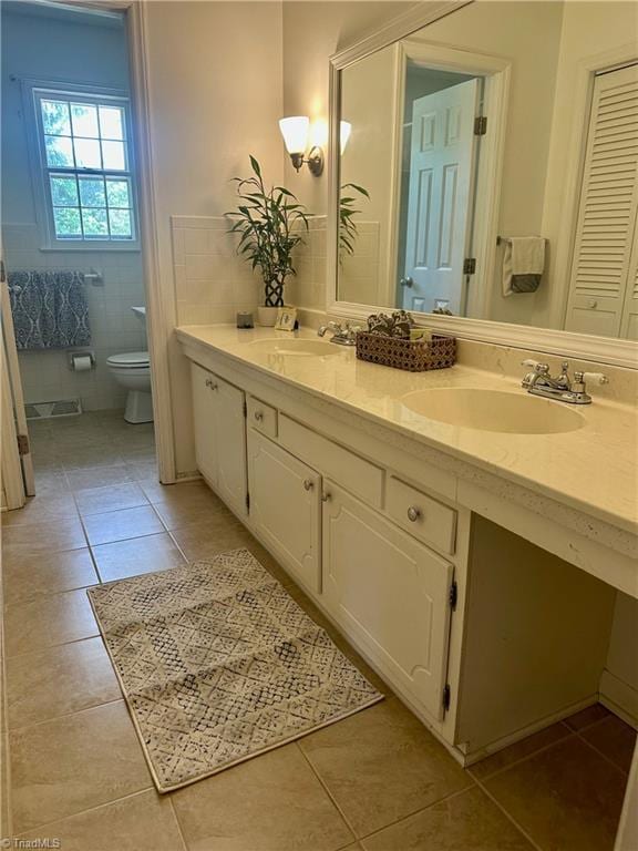 bathroom featuring toilet, tile patterned flooring, double vanity, and a sink