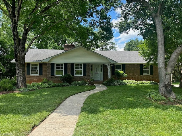 single story home featuring brick siding, a front lawn, and a chimney
