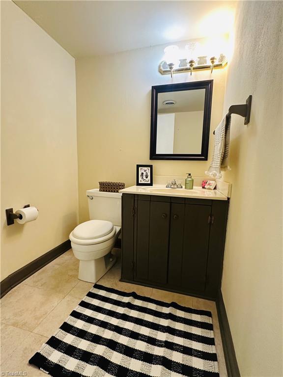 bathroom featuring toilet, baseboards, tile patterned floors, and vanity