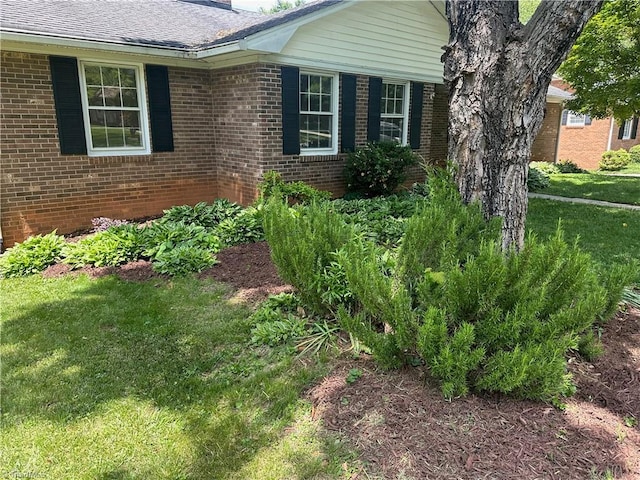 view of property exterior with a yard, a chimney, and brick siding