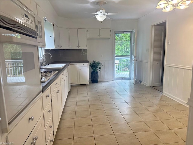 kitchen with white cabinetry, light tile patterned flooring, ceiling fan with notable chandelier, and a sink