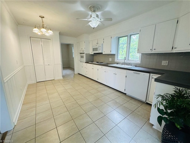 kitchen featuring light tile patterned floors, white appliances, a sink, backsplash, and dark countertops